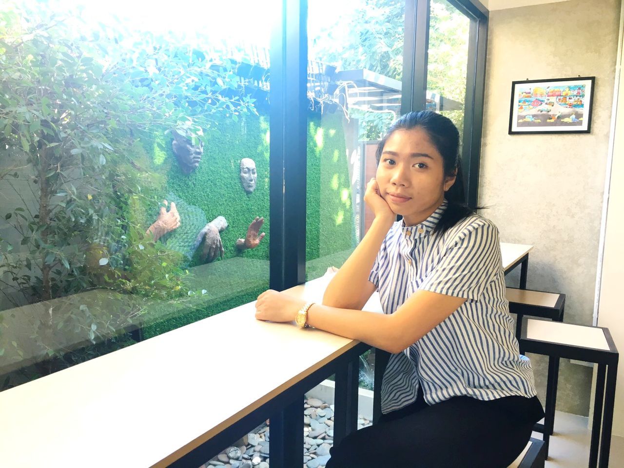 WOMAN LOOKING THROUGH WINDOW WHILE SITTING ON TABLE AT HOME