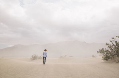 Rear view of woman standing in desert