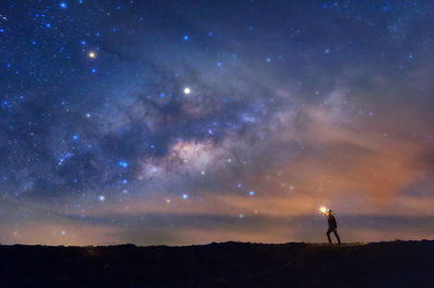 Silhouette people standing against star field at night