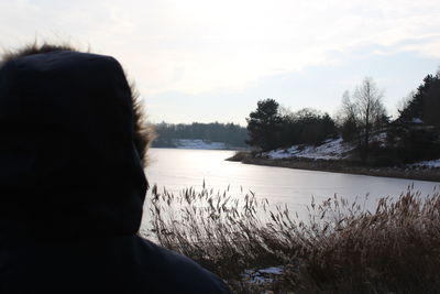 Rear view of girl in lake against sky during winter