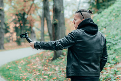 Young man blogging while standing in forest