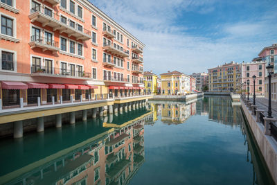 Reflection of buildings in canal against sky