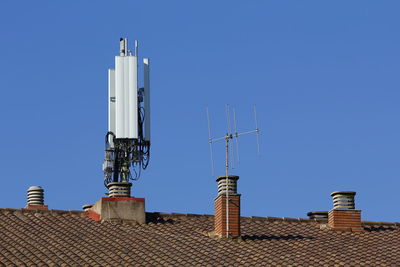 Low angle view of telecommunication tower on roof against sky