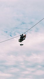 Low angle view of overhead cable cars against sky