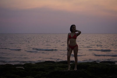Full length of woman standing on beach during sunset