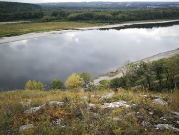 Scenic view of lake and landscape against cloudy sky