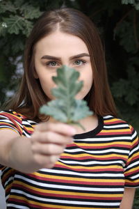 Portrait of young woman holding plant