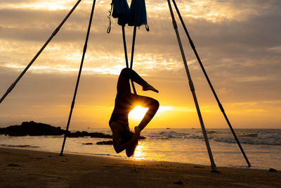 Silhouette man on beach against sky during sunset