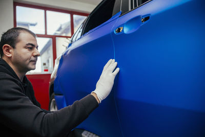 Man examining car wrapped with vinyl foil