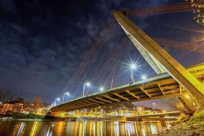 Low angle view of illuminated bridge over river at night