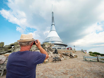 Aged photographer use vintage photographic equipment during trip on mountain summit. 