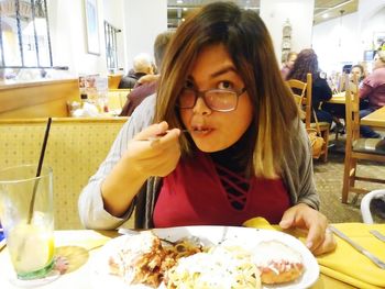 Portrait of young woman eating food in restaurant