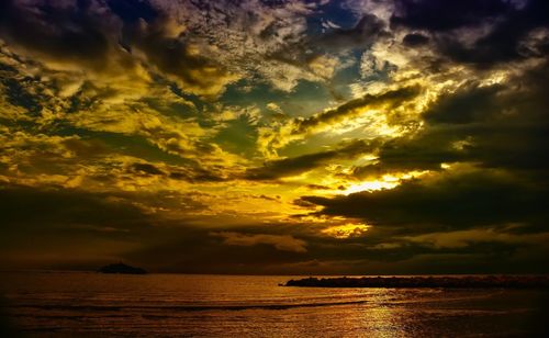 Scenic view of sea against dramatic sky during sunset