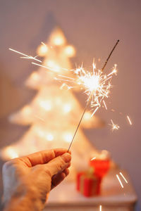 Cropped hand holding sparkler at night