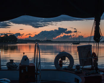 Silhouette sailboats moored in sea during sunset