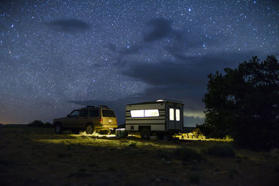 Car and illuminated travel trailer against star field