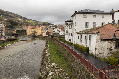 Canal amidst houses in town against sky