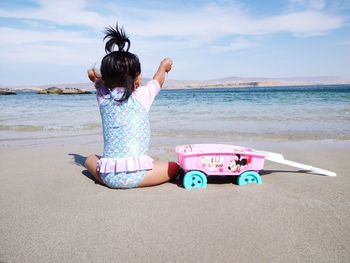 Rear view of woman on beach against sky