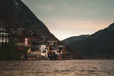 Buildings by sea against sky at sunset