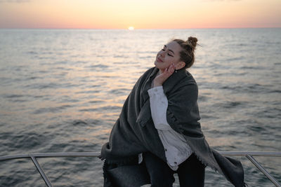 Young woman standing against sea during sunset