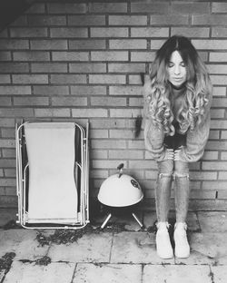 Young woman sitting on brick wall