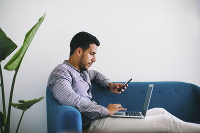 Young man looking away while sitting on mobile phone
