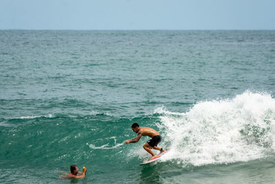 Man surfing in sea against sky