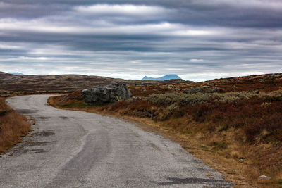 Road leading towards mountains against sky