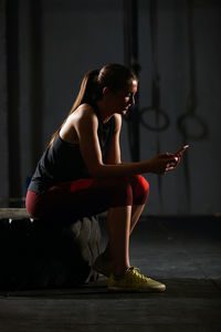 Full length of woman using mobile phone at gym