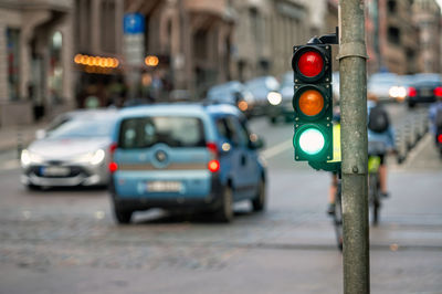 A city crossing with a semaphore on blurred background with cars in the evening streets, green light