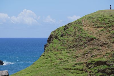 Scenic view of sea by mountain against sky