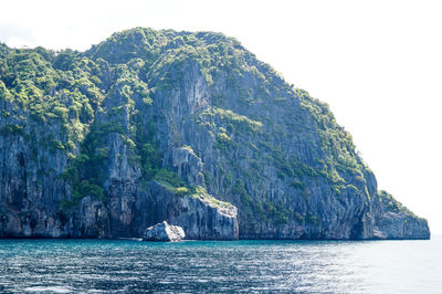 Rock formation by sea against sky