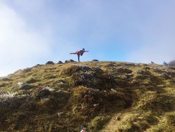 Low angle view of person paragliding on mountain against sky