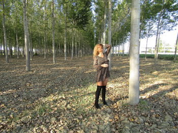 Full length of woman standing amidst trees in forest