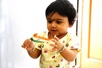 Cute baby girl holding flag at home