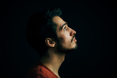 Close-up of thoughtful young man against black background