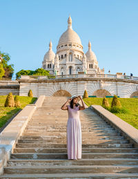 Rear view of woman standing by fountain against clear sky