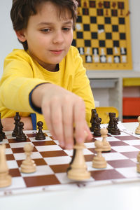 Caucasian boy playing chess. happy concentrated child behind chess in class or school lesson