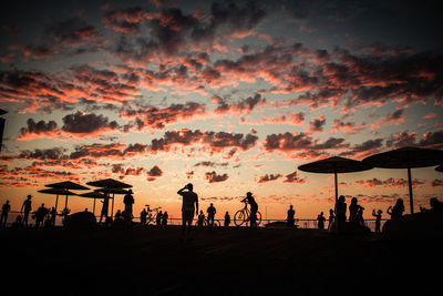 Silhouette people on beach against sky during sunset