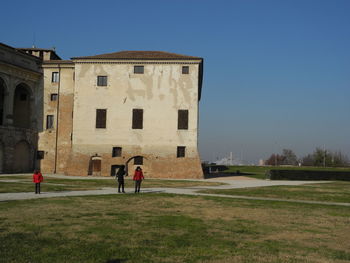 People playing in front of building against clear sky