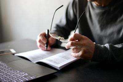 Midsection of man using mobile phone while sitting on table