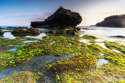 Rock formation by sea against sky