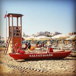 Boats moored on beach against clear sky