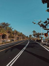 Empty road along trees and against sky