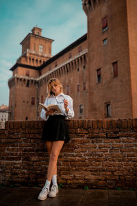 Full length of woman standing against brick wall