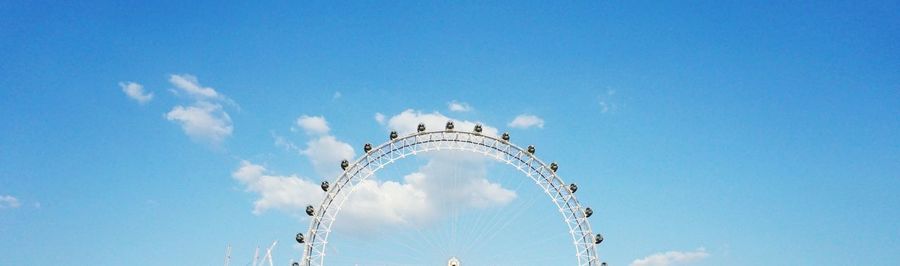 Low angle view of ferris wheel against blue sky