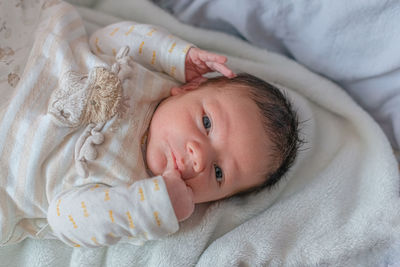 Newborn baby lies on a blanket in his bed