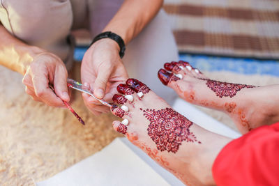 Cropped image of beautician making henna tattoo on bride leg