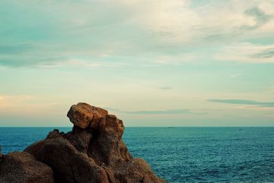 Rock formation on beach against sky during sunset