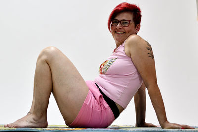 Portrait of smiling woman sitting against wall